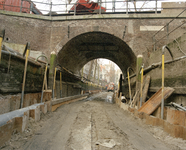 801008 Gezicht in de, vanwege de aanleg van de riolering, drooggelegde Nieuwegracht te Utrecht, bij de Paulusbrug.